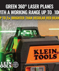 Compact self-leveling laser level with bright green cross lines, 360-degree planes, mounted on a wall, orange casing, Klein Tools logo.