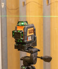 Side view of a compact self-leveling laser level with bright green cross lines and 360-degree planes delivering precise alignment on tripod.