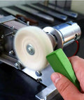 Hand holding green buffing compound bar for metal polishing against rotating buffing wheel on metal surface