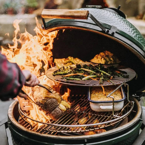 Open grill with sizzling vegetables, meats, and fire inside an Original Large Green Egg, barbecue scene.