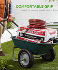 Person using green dual wheel garden cart with a load of garden soil and hose, demonstrating comfortable grip and utility.