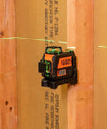 Compact self-leveling laser level with bright green cross lines and 360-degree planes on wood surface for construction alignment.