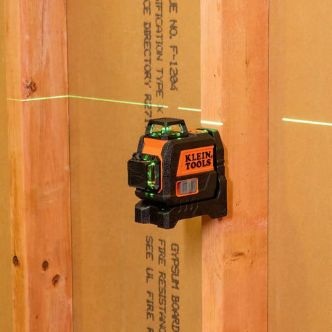 Compact self-leveling laser level with bright green cross lines and 360-degree planes on wood surface for construction alignment.