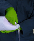 Person using Green Nitrile Latex Free Gloves 8 Mil Heavy Duty Raised Diamond Texture Box 100, pouring liquid detergent in laundry setting