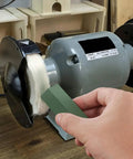 Person using a green compound from triple bar metal polishing kit with 4 oz total on a buffing wheel for smooth finish on metal.