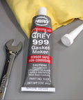 Heavy Duty High Temp RTV Silicone Sealant And Gasket Maker 650 Degrees F OEM Specified Sensor Safe Non Corrosive Neutral Cure Low Odor 3 Oz Tube Grey Sealant For Head Gaskets Oil Water Anti Freeze Resistant on table with wrench.
