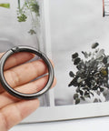 Hand holding a large 3-inch round carabiner clip in gun black, used for keychains, bags, purses, and DIY charms, crafts making.