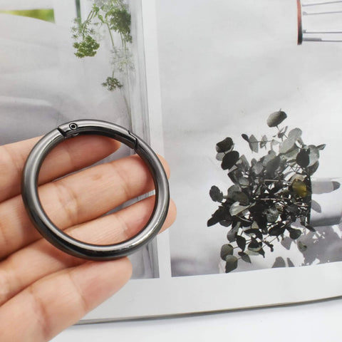 Hand holding a large 3-inch round carabiner clip in gun black, used for keychains, bags, purses, and DIY charms, crafts making.