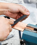 Flat 6 Inch Hand File With Double Cut Teeth And Single Cut Edge Made From High Carbon Steel used for shaping copper in workshop.
