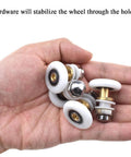 Hand holding 27mm diameter brass shower door wheels with nylon rollers, stainless steel screws and ball bearings