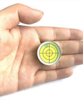 Compact 1.2 inch bullseye bubble level with aluminum alloy housing held in hand, showing green target design with 30 ft / 2 mm precision