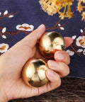 Hand holding Tianigo Copper Baoding Balls Set, 1.57 Inches Chinese Health Balls, Metal Stress Relief Hand Massage Balls No Chime for Hand Exercise