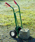 4.10/3.50-4 Flat Free Tire and Wheel Set of 4 installed on a green hand truck with red handles on gravel surface.