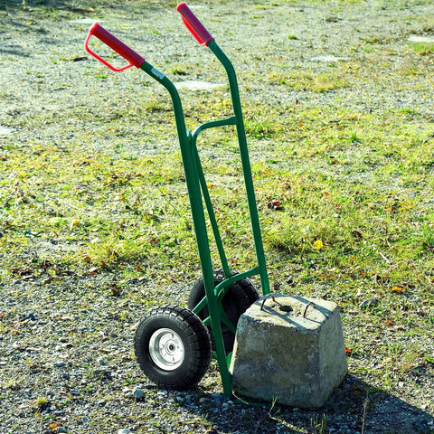 4.10/3.50-4 Flat Free Tire and Wheel Set of 4 installed on a green hand truck with red handles on gravel surface.