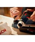 Efficient Three And A Quarter Inch Planer Kit Delivers Precise Stock Removal With A Powerful Six Point Five Amp Motor And Sixteen Thousand Five Hundred RPM Featuring A Dual Mount Guide Fence And Woodrazor Blades To Create Smooth Straight Edges On Doors being used on wood surface.