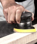 Person using 120 Grit Mouse Detail Sander Sandpaper 50 Pcs 5 Hole Hook And Loop 140mm Sheets on wood surface.