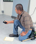 Man using Precision Handheld Ultrasonic Distance Meter For Fast Measurements With A 50 Foot Range That Quickly Displays Length Area And Volume In A Compact Unit Ideal For Painters Builders Flooring Pros And DIY Enthusiasts DM S50 in a room