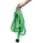 Person holding green expandable garden hose with nozzle, using Spring Ratchet Cable And Hose Clamp Organizer With Spring Loaded Wrap System