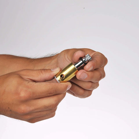 Person holding a small brass precision tool with a knurled adjustment knob.
