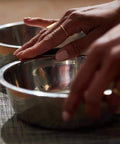 Hands holding stainless steel bowls on a textured mat