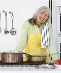 Woman cooking in kitchen with stainless steel utensils and pots on the stove