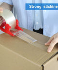 Person using Heavy Duty Clear Packing Tape 2 Rolls With Refillable Dispenser Noiseless 1.88 In X 55 Yards Shipping Tape on box.