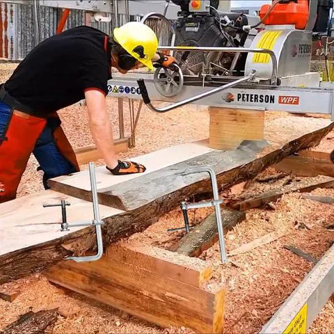 Person using Heavy Duty 12 Inch F Clamp Set 4 Pack For Welding Woodworking And Metalworking 1320 Lb Load Capacity on a wooden plank.