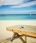 Front view of marine-grade stainless steel folding D-ring tie on a wooden table at the beach.