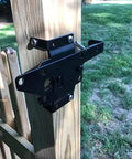 Beefy Heavy Duty Self Locking Gate Latch for wooden fence post mount, shown installed on a wooden fence, black finish.