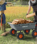 Man using 800 lb Poly Dump Garden Cart Heavy Duty Yard Dump Wagon 4 Wheel Wheelbarrow with Steel Frame loaded with firewood in a field.