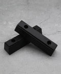 Two black Beefy Rubber Bump Stop Buffer For Heavy Doors And Vehicles Anti Collision Block For Trucks Trailers Motorhomes Steel Doors Industrial Use 210x50x50mm on concrete surface.