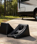 Heavy Duty Wheel Chocks For Cars And Travel Trailers, Stackable Space Saving Anti Slip Wedges With Rock Solid Grip, 8x4.7x4.7 Inches, 4 Pack, Black By TONDA in front of a travel trailer on a driveway.