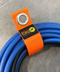 Close-up of blue cable secured with Heavy Duty Wrap It Storage Strap 10 Inch Blaze Orange for garage organization.