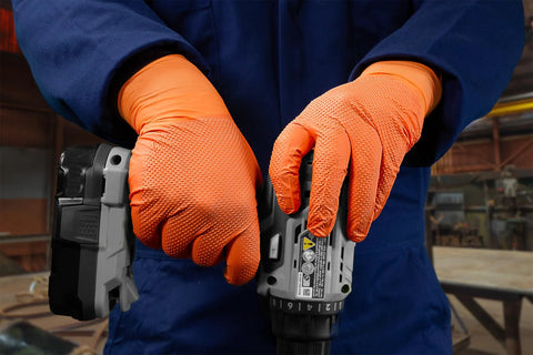 Person wearing Hi Vis Orange Nitrile Gloves Raised Diamond Texture 8 Mil using a power tool in workshop