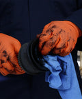 Worker wearing Hi Vis Orange Nitrile Gloves Raised Diamond Texture 8 Mil, holding tools in a mechanic shop