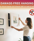 Person hanging a frame using damage-free hook-and-loop tape, illustrating use for mounting without nails or screws.