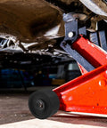 Universal Steel Front Wheel Replacement For Hydraulic Floor Jacks 2.5 Ton To 3.5 Ton installed on a red hydraulic jack lifting a car
