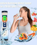 Woman using hydrogen water tester kit to measure water quality with pH, H2, ORP, and temperature readings, surrounded by fresh fruits.