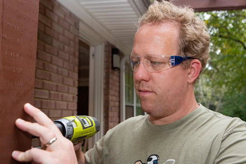 Man wearing Impact Resistant Safety Glasses With UV400 Anti Fog Clear Lenses ANSI Z87.1 using a drill outdoors at a work site
