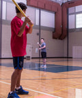 Indoor practice with 9" Hollow Plastic Baseballs - Athletic Baseball Equipment in gym, player ready to bat with a lightweight plastic bat.