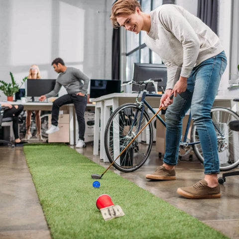 Person practicing putting with Practice Golf Balls 24 Pack, 42mm Plastic Golf Balls in a multicolor set on an indoor green in an office space.