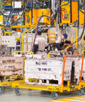 Industrial workshop with workers operating machinery and using heavy duty platform trucks with 5 by 2 inch casters.