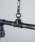 Close-up of Rustic Industrial Tube Pipe Chandelier With Five Light Edison Style Steampunk Pendant Light Fixture For Dining Room.