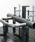 Inserta Clamp For Eight And A Half Inch Capacity By Build Pro UEN5200 holding metal pipe securely on a perforated table.