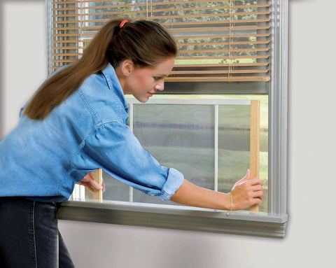Woman installing Adjustable Window Screen For 25 To 45 Inch Wide Openings, 10 Inch High, 2 Pack, Marvin Style with wood ends.