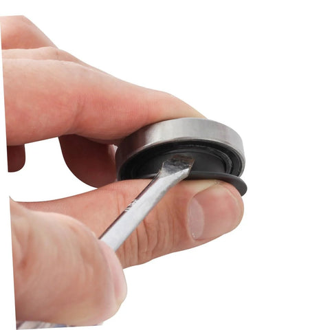 Close-up of hand holding bike bearing and axle protection cover with tool, from Two Pack Black Axle Protection Covers for Bike Bearings Dust Covers