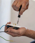 Person using screwdriver to fix electrical outlet, highlighting use of machine screws in installations