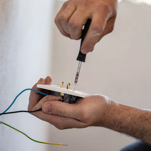Person using screwdriver to fix electrical outlet, highlighting use of machine screws in installations