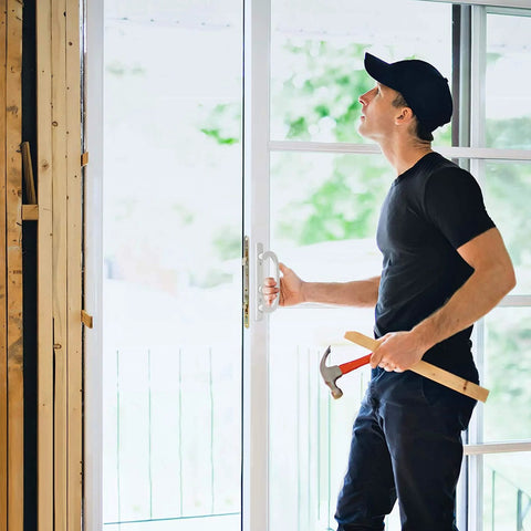 Installer working on 2 Point Sliding Patio Glass Door Mortise Lock with 11-3/4" Faceplate, holding a hammer, during installation.