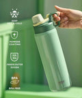 Hand holding insulated stainless steel water bottle with spout lid and easy grip handle for sports on the go, green color.